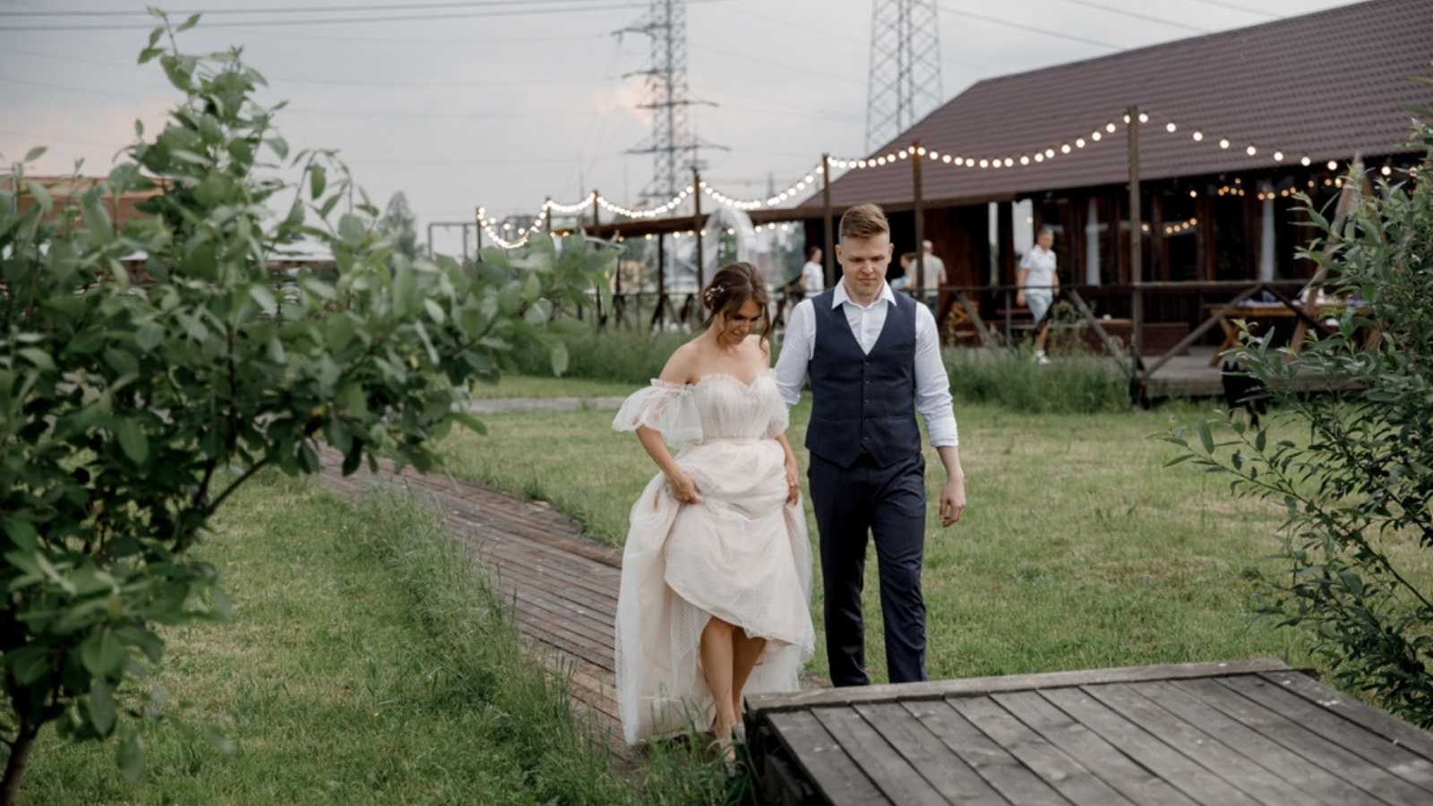 Wedding couple bride and groom walk against wooden barn of stormy sky Rustic country eco-friendly wedding. Copy space for design and advertisement