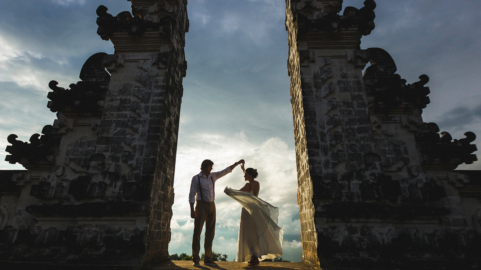 Bali Travel concept. Balinese famous symbol - traditional gate in temple. Welcome in Bali. Couple in love at sunset.