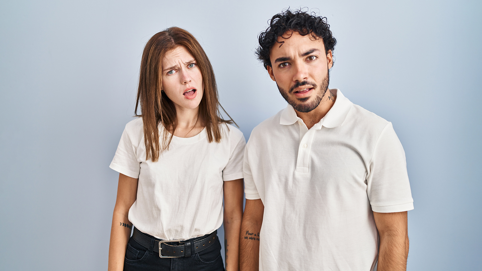 Young couple wearing casual clothes standing together in shock face, looking skeptical and sarcastic, surprised with open mouth