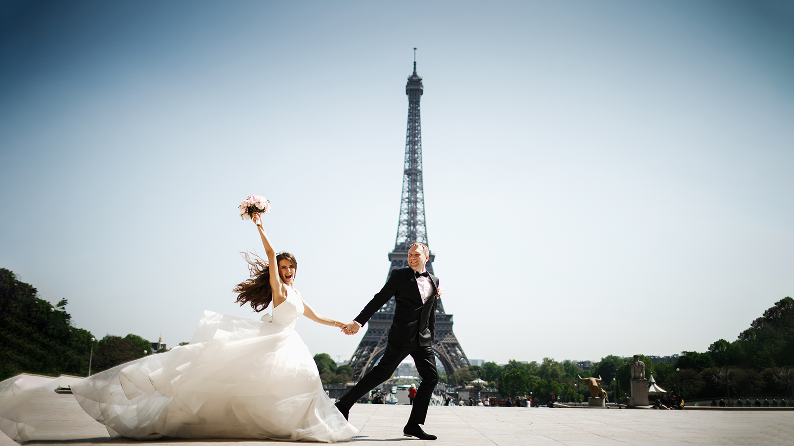 Bride and groom run before the Eiffel tower in Paris