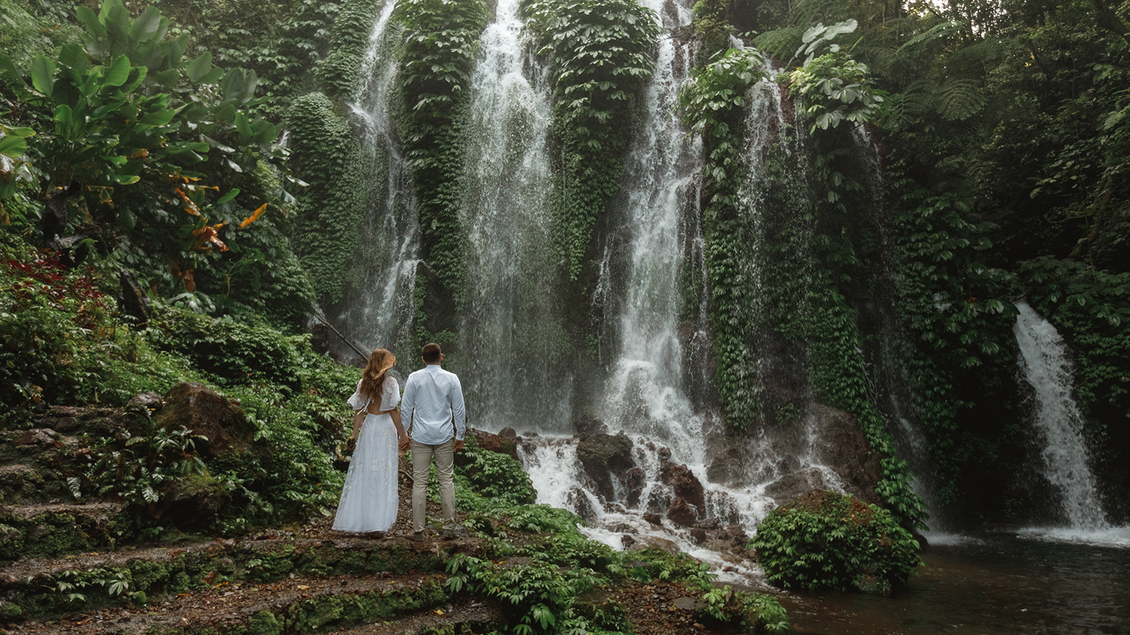A couple in love on a waterfall. Honeymoon trip. Happy couple on the island of Bali. Beautiful couple travels the world. Travel to Indonesia. Happy couple on vacation. Wedding trip