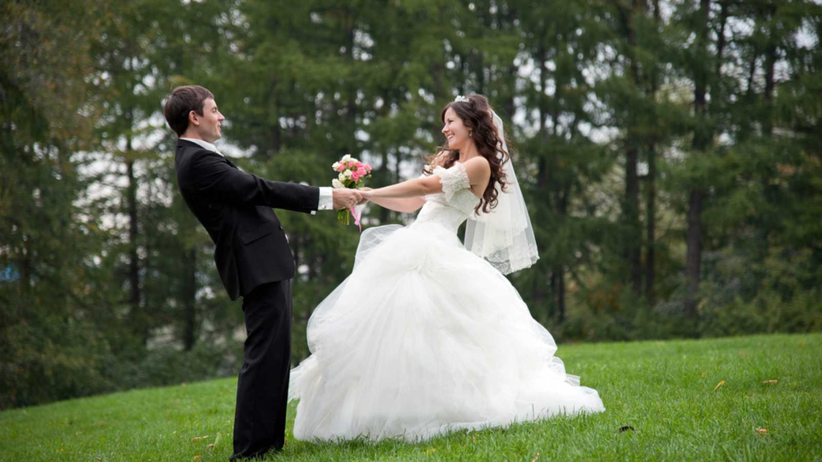 Bride and groom dancing in field