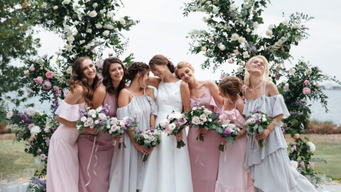 Beautiful elegant slim smiling bridesmaids in delicate pink beige summer dress on the wedding ceremony