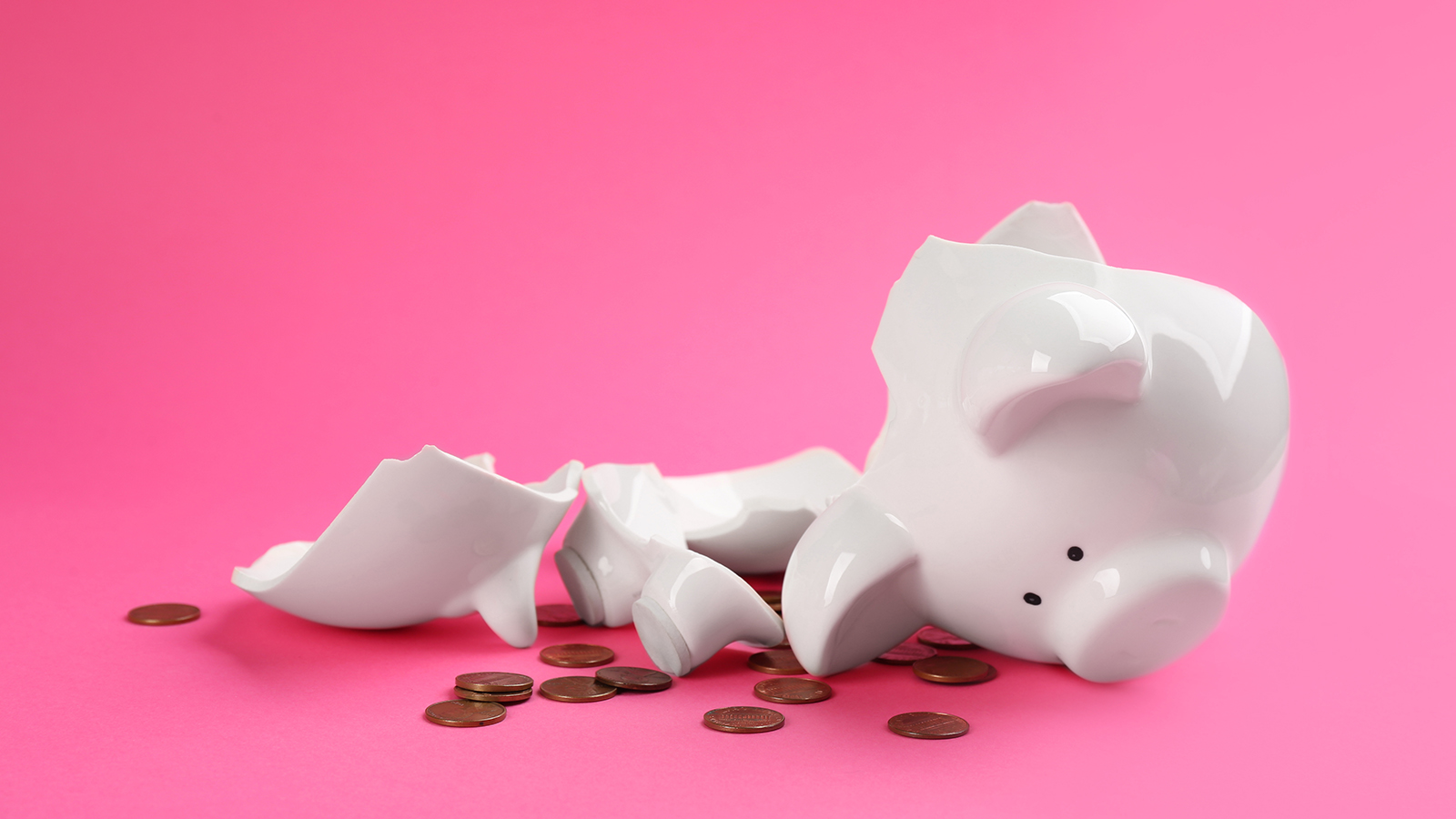 Broken piggy bank with coins on pink background