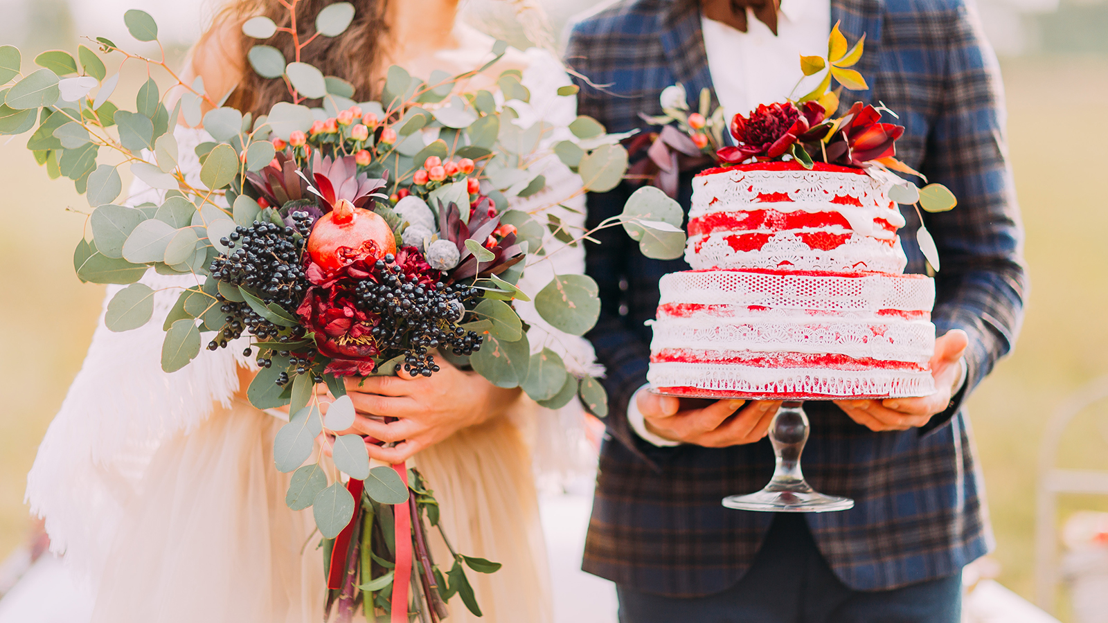 Wedding couple holds beautiful cake and bouquet close up.