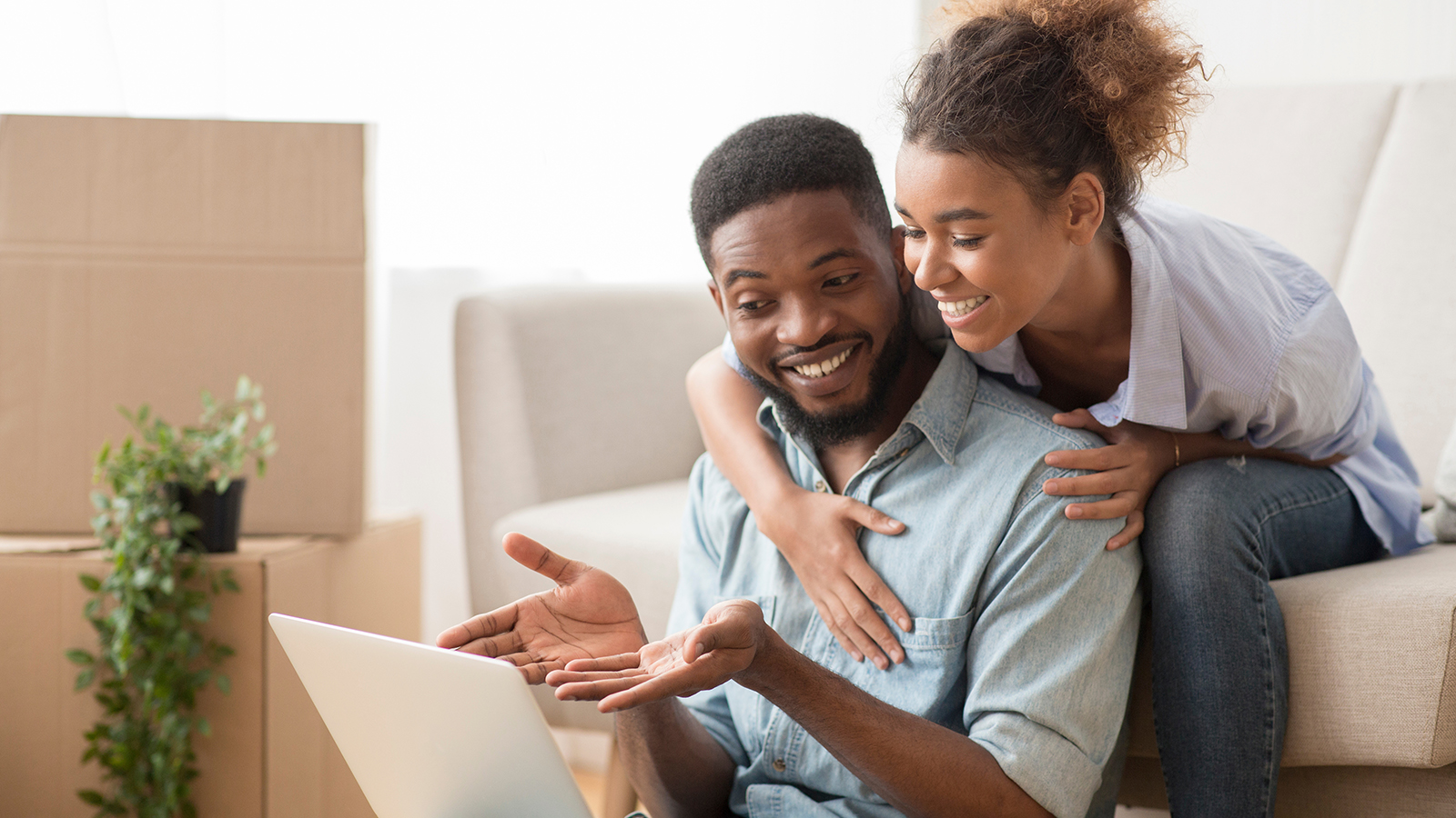 Smiling Black Husband Using Laptop Showing Something His Wife Sitting On Couch
