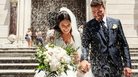 People throw rice on newlyweds walking out of the church