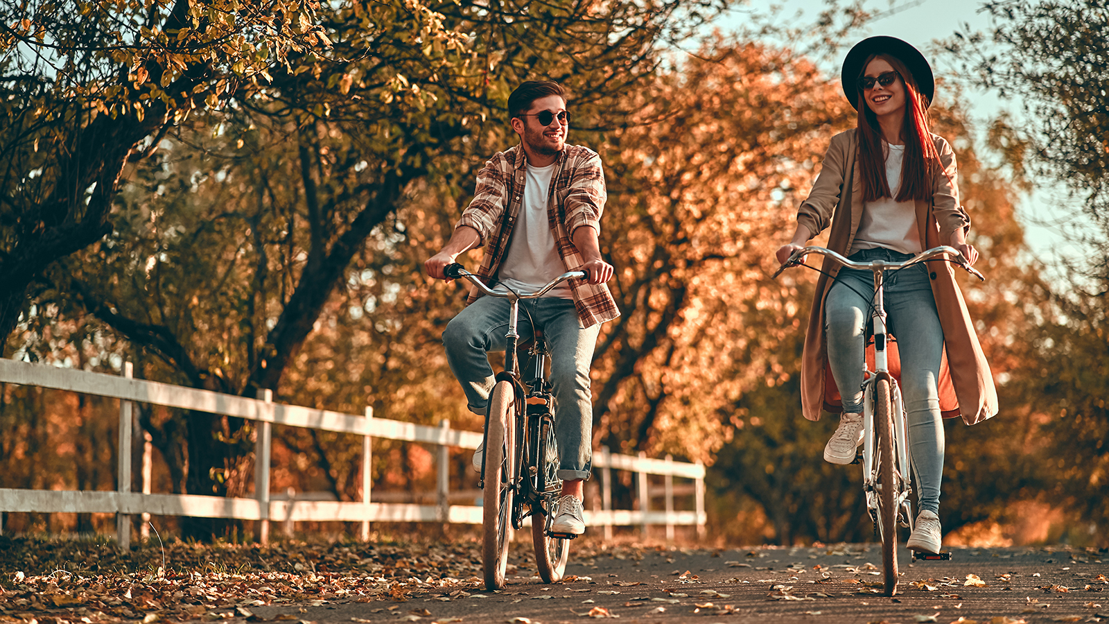 Young couple with bicycles in park in autumn time. Teenagers having romantic date.