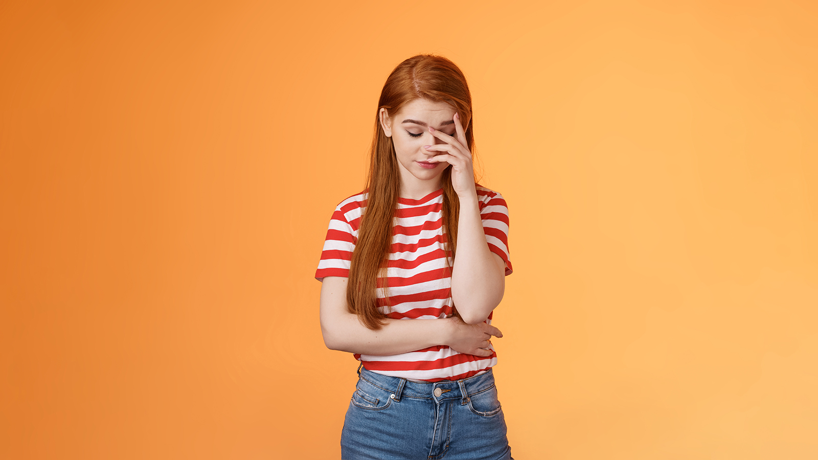 Annoyed redhead woman fed up listening stupid nonsense, close eyes tired, make face palm embarrassed uninterested, feel uneasy distressed, exhausted useless argument, irritated orange background.