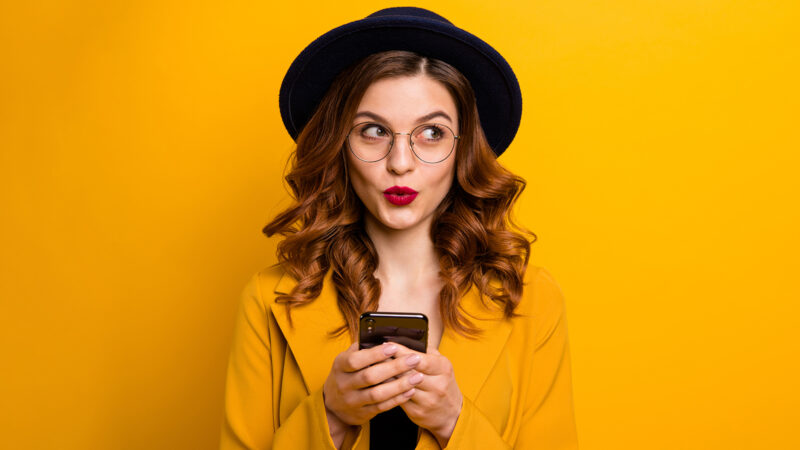 Close up photo beautiful she her lady watch sly tricky side empty space arms hands telephone reader cool news modern look wear specs formal-wear costume suit isolated yellow vibrant background