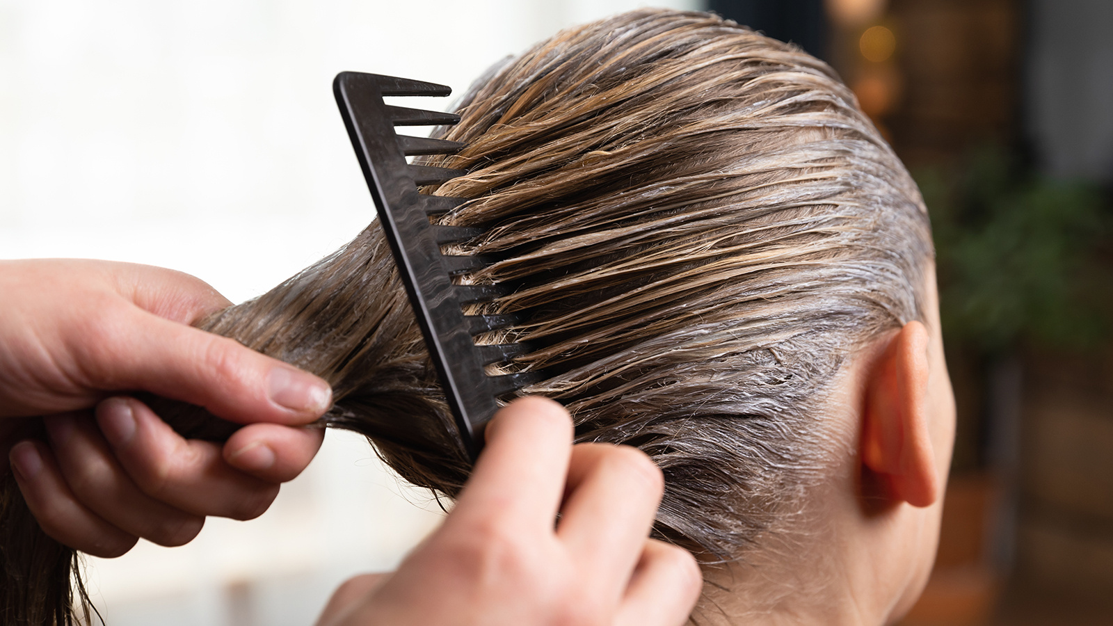 Hairdresser doing treatment after applying hair coloring , hair dye for a blonde women at home or salon.