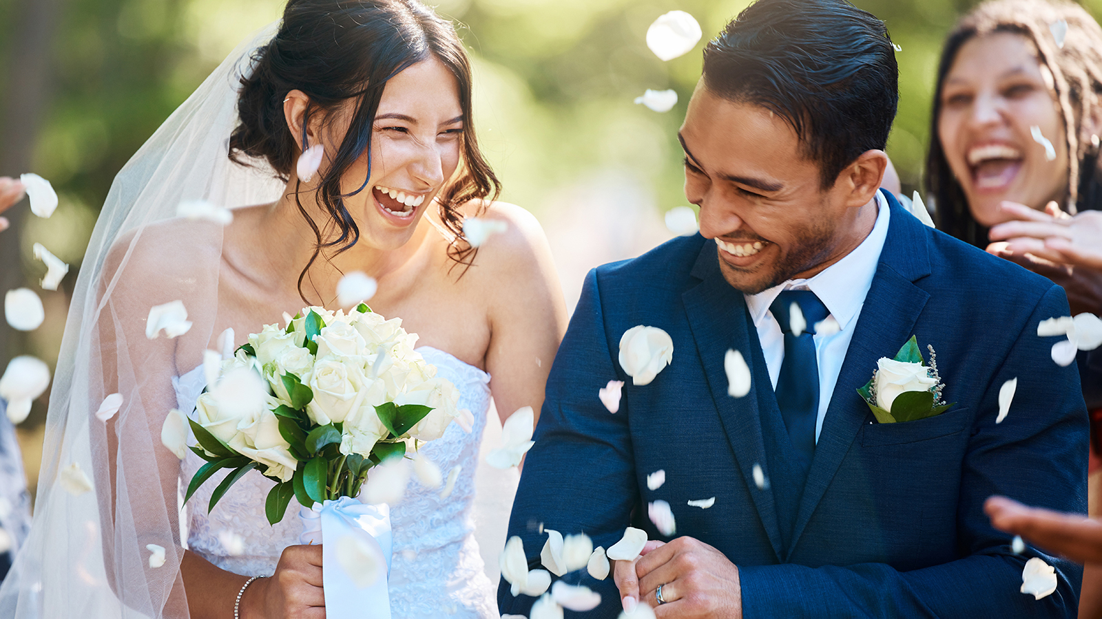 Love, wedding and couple walking with petals and guests throwing in celebration of romance. Happy, smile and young bride with bouquet and groom with crowd celebrating at the outdoor marriage ceremony.