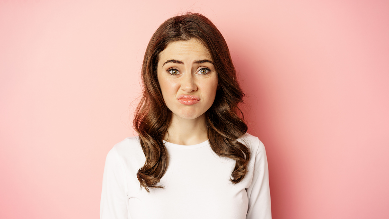 Close up portrait, face of woman cringe, grimacing disappointed, looking awkward or upset, standing over pink background