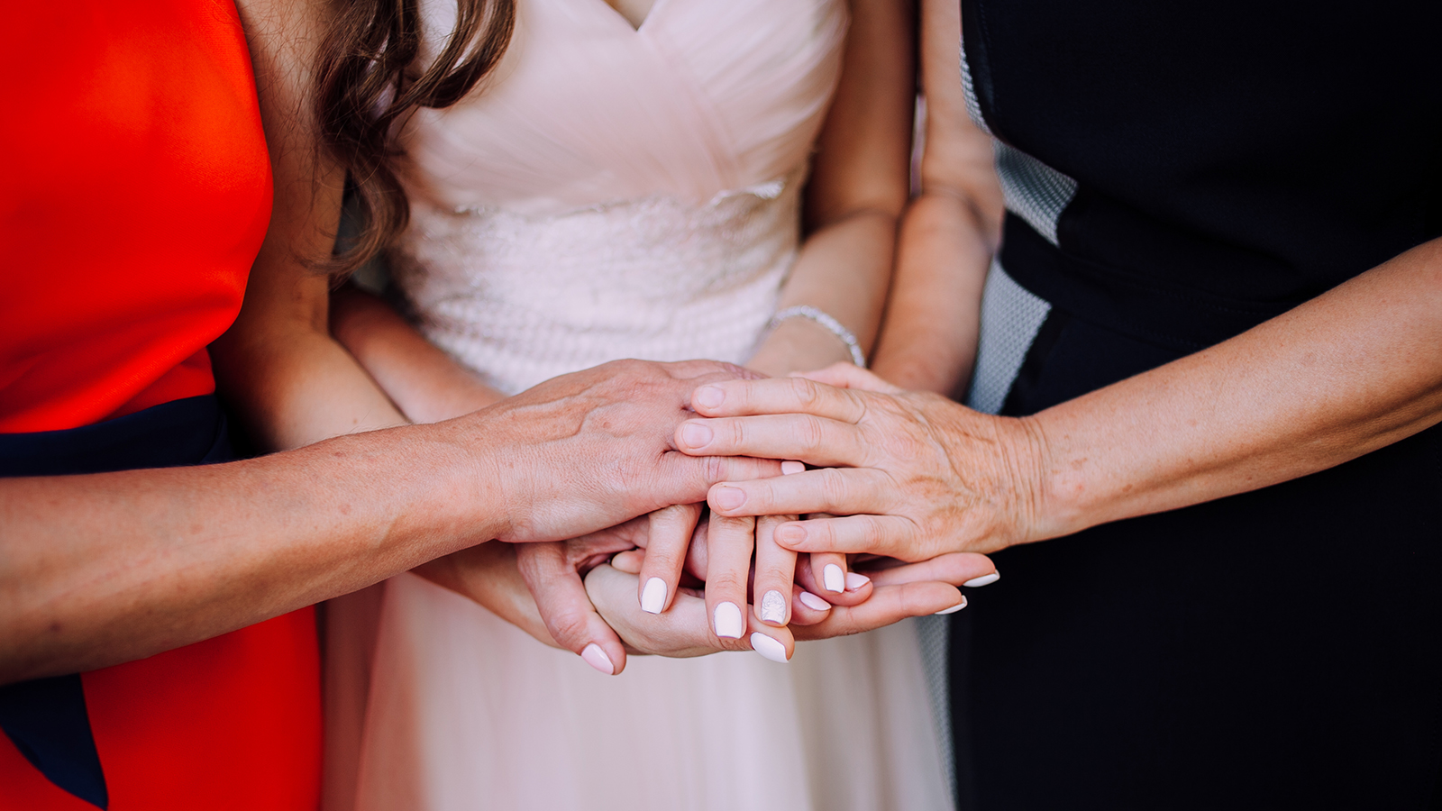 Mother, bride, mother-in-law holding hands. Wedding. The concept of love.