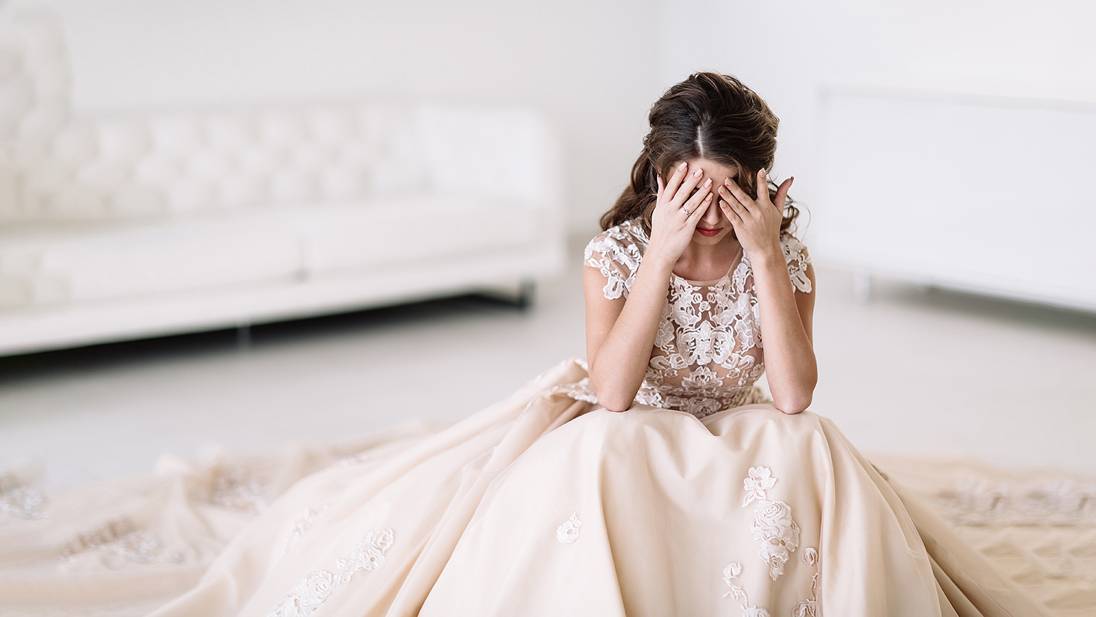 the bride sits in a white room and is sad. Natural light. covers