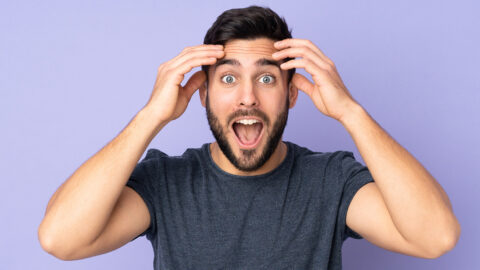 Caucasian handsome man with surprise expression over isolated purple background