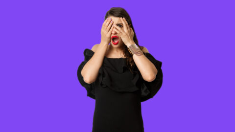 Fashion and beauty. Shocked young woman in black dress covering eyes, peeking through fingers at something embarrassing, cringe, standing over white background