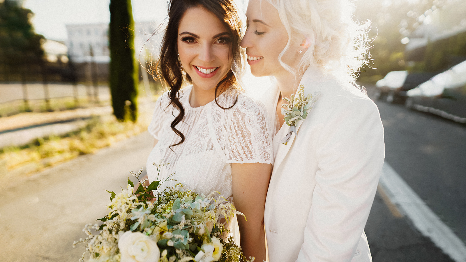 Just married lesbian couple is hugging outdoors and holding big bridal bouquet