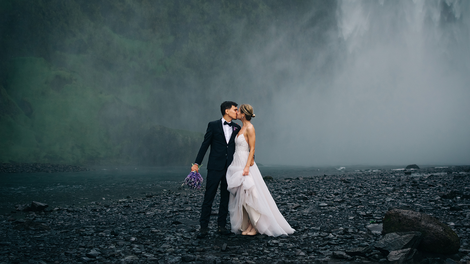 Young happy wedding couple kissing on background of waterfall, o