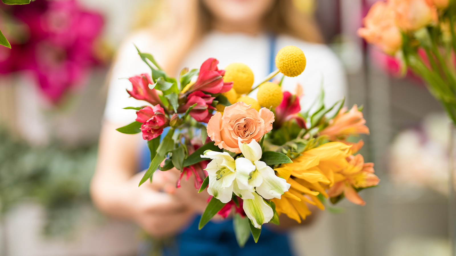 Proud woman showing her florist skills holding a colorful natural bouquet. Seen up close