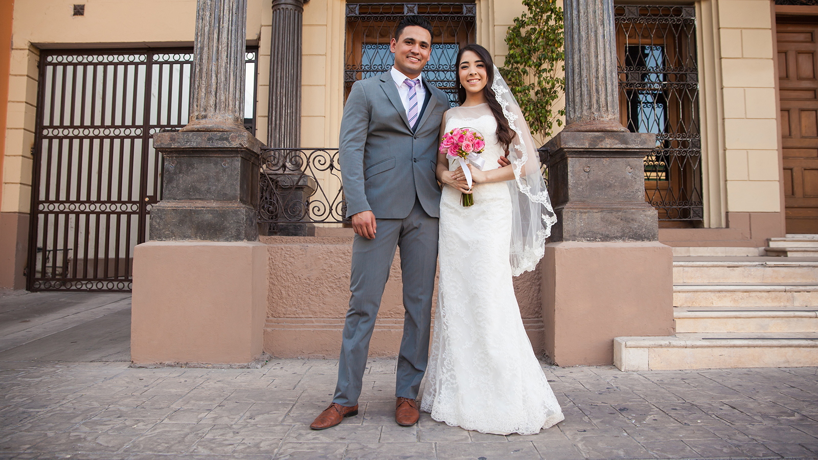 Young Latin bride and groom standing together outside a courthouse on their wedding day