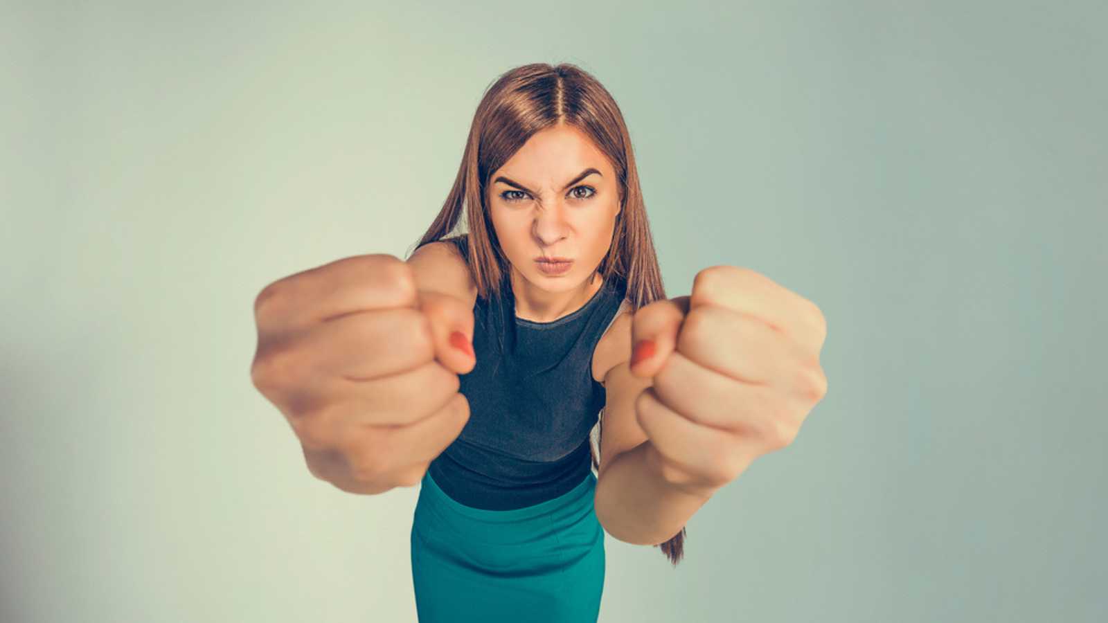 angry young woman showing fists about to punch hit someone 
