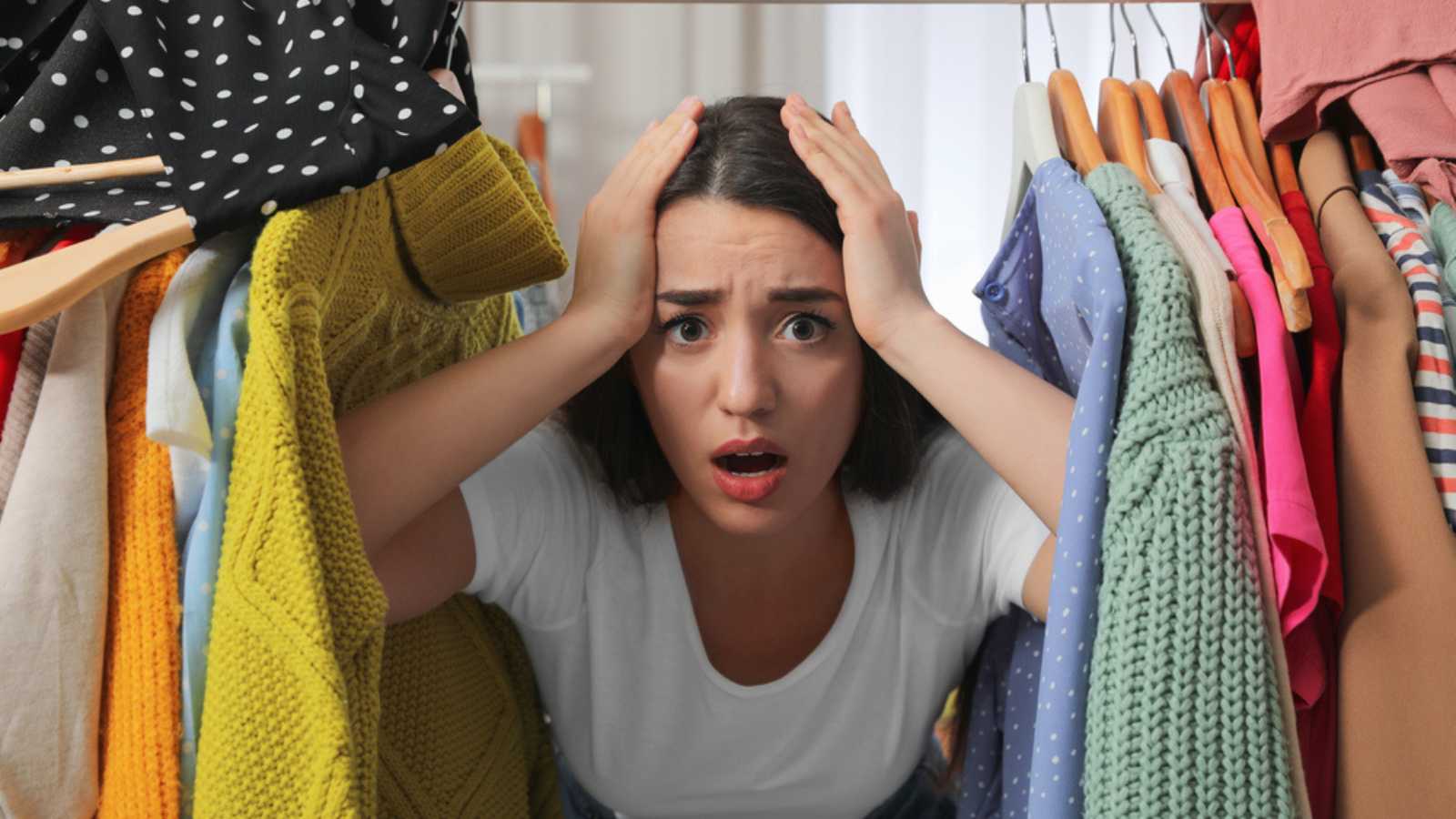 Upset young woman with lots of clothes