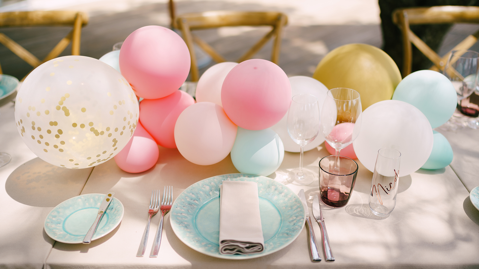 Wedding dinner table reception. Blue plates with a pattern and a napkin, on a cream tablecloth. Little balloons on the table. Serving a table for a bachelorette party.