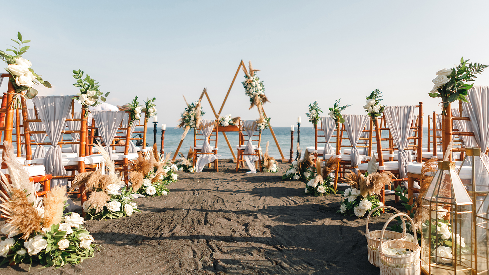 Triangular wedding arch by the sea ready for the ceremony. Wedding ceremony setup on black sand beach