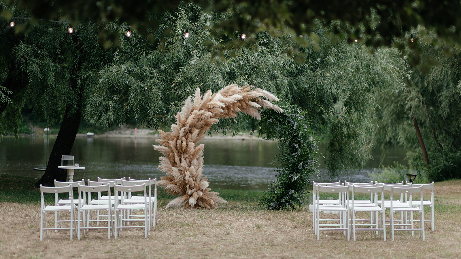 Wedding arch under the tree and chairs for guests. Outside ceremony place. Wedding arch. Wedding ceremony place