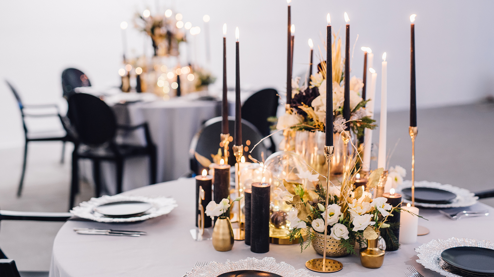 Black candles on candlesticks with flowers in vases on reception table. Wedding. Decor