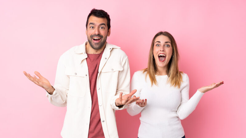 Couple in Valentine Day over isolated pink background with surprise and shocked facial expression