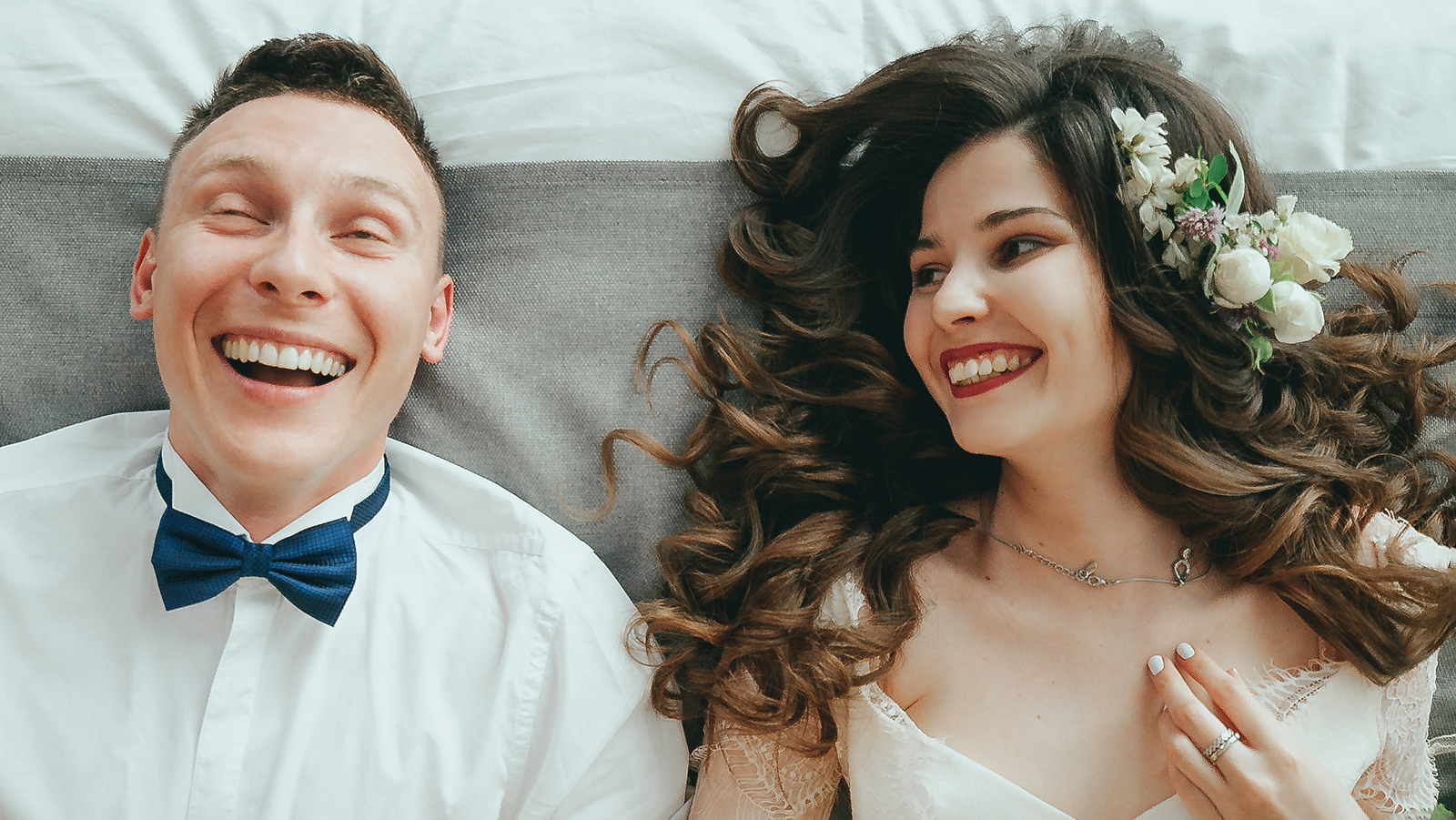 Stylish bride and groom are lying on the bed. Laughter and fun