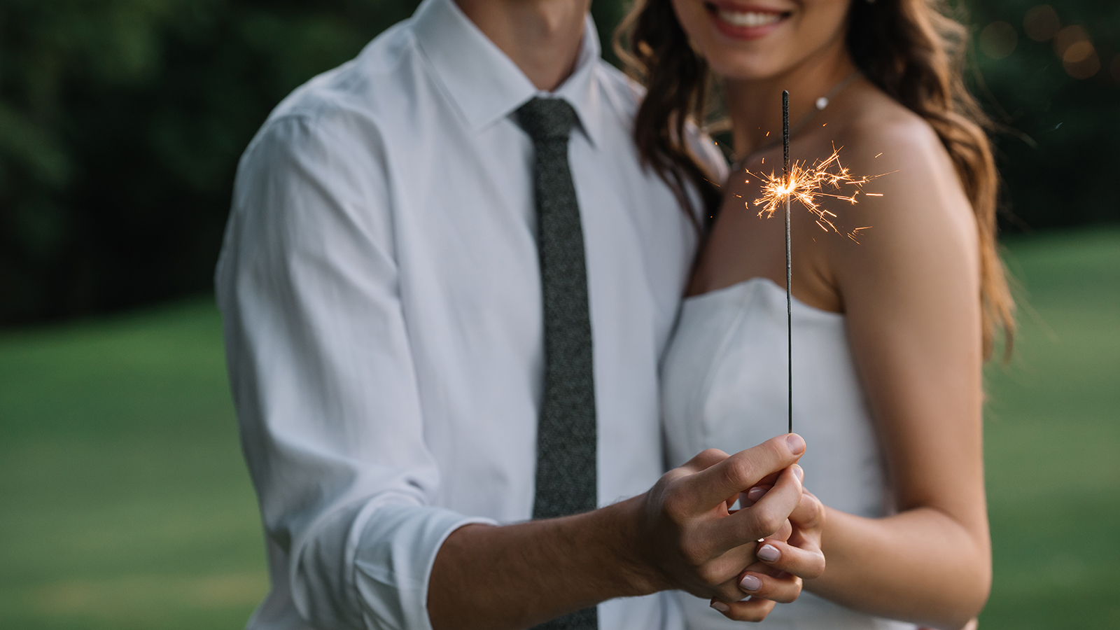 cropped shot of smiling young wedding couple holding sparkler