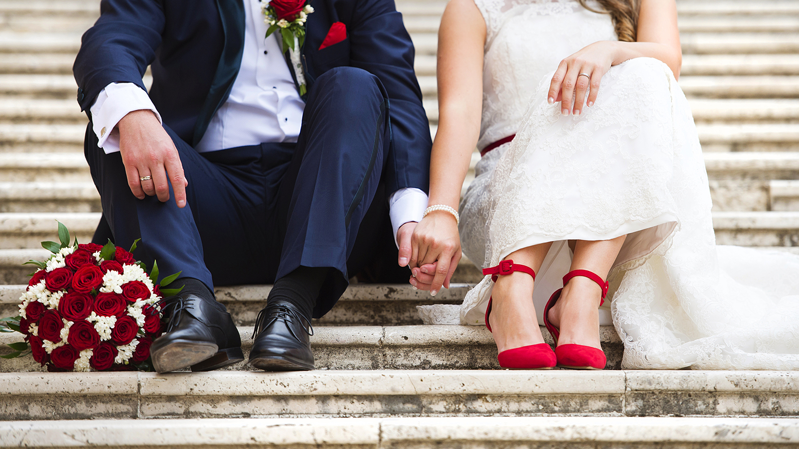 Unrecognizable young wedding couple holding hands as they enjoy romantic moments outside on the stairs