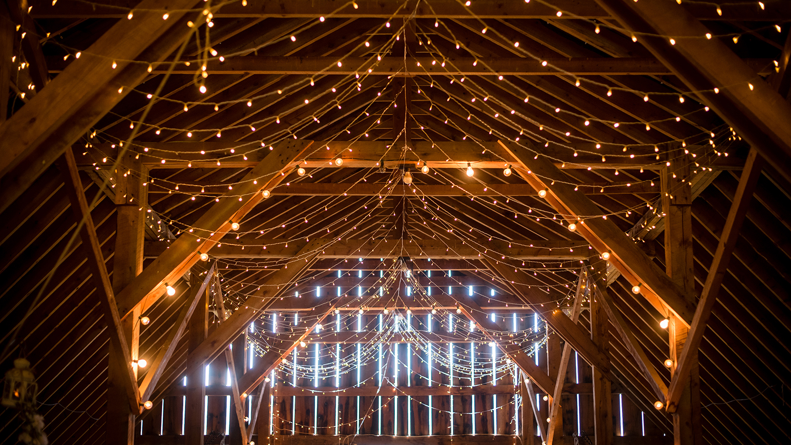 Indoor barn wedding with beautiful cafe string lighting in elegant setting to celebrate marriage of love in a rustic setting