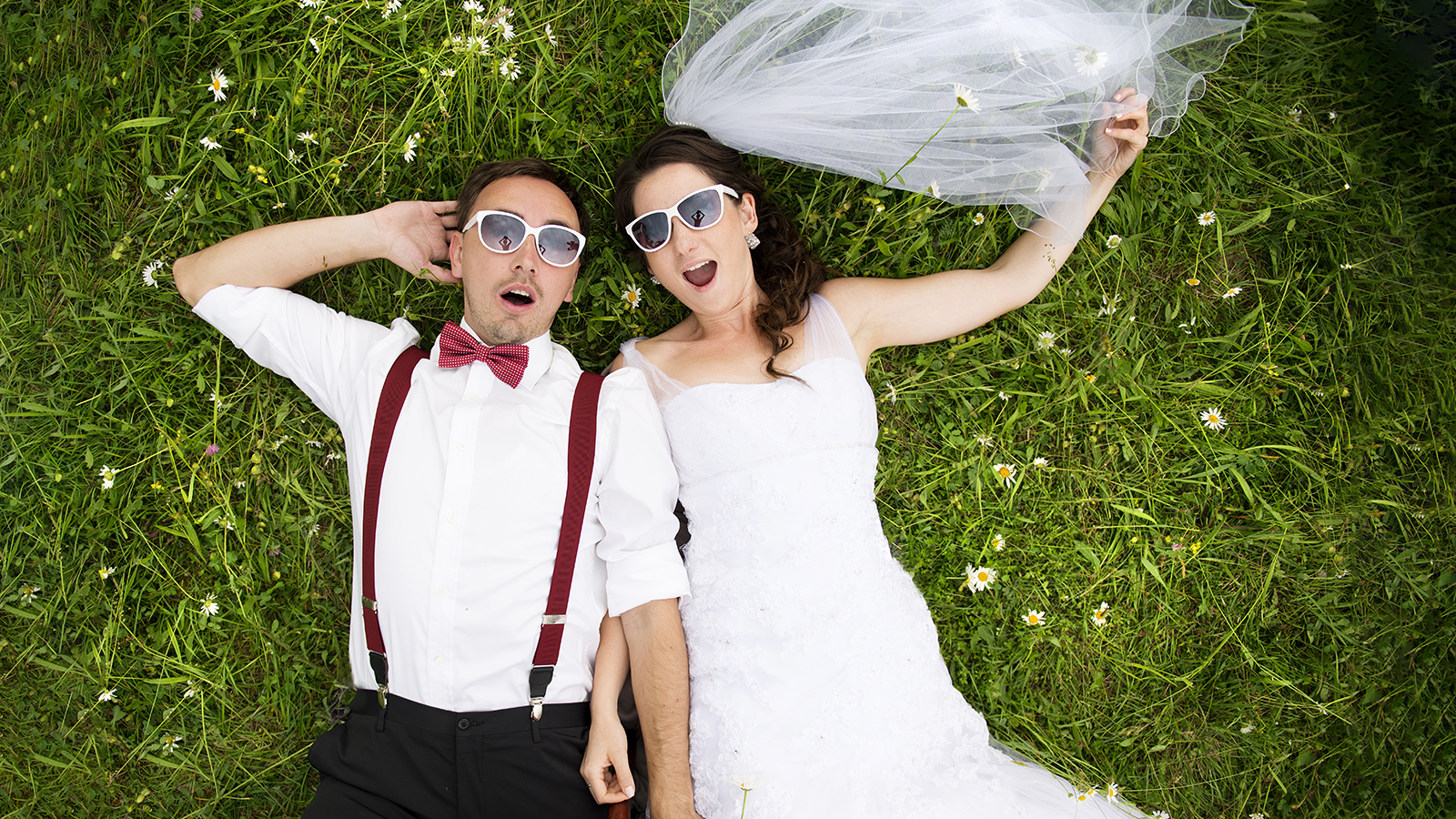 fun wedding couple on grass with sunglasses