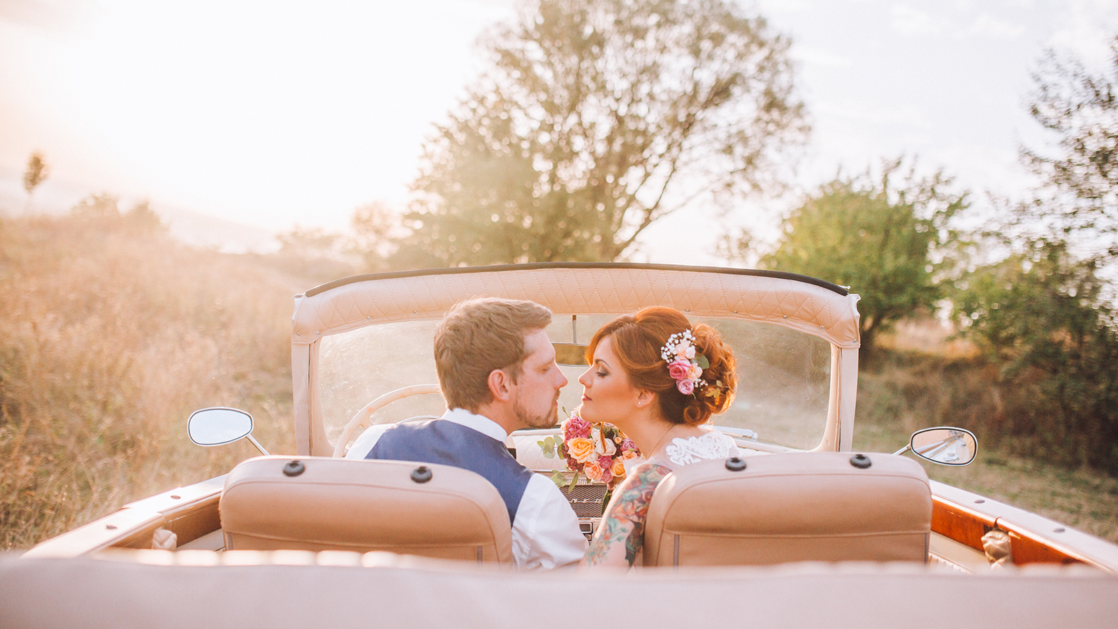 Stylish Loving wedding couple kissing and hugging on nature near retro car
