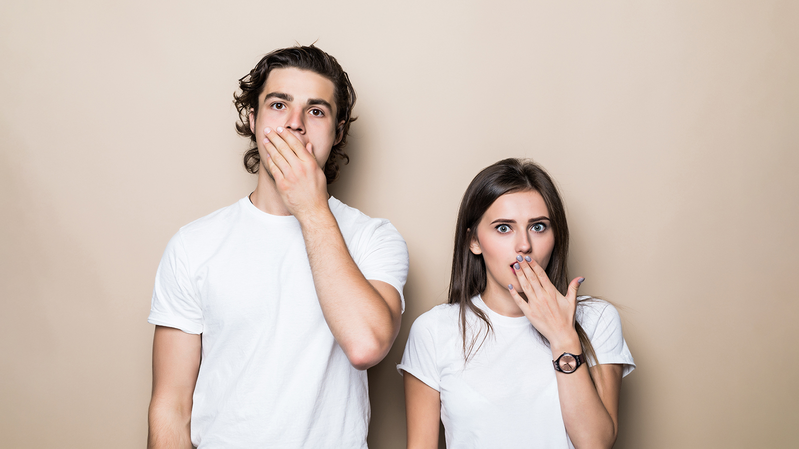 Portrait of attractive couple wearing white t-shirt great news delight reaction over beige color background