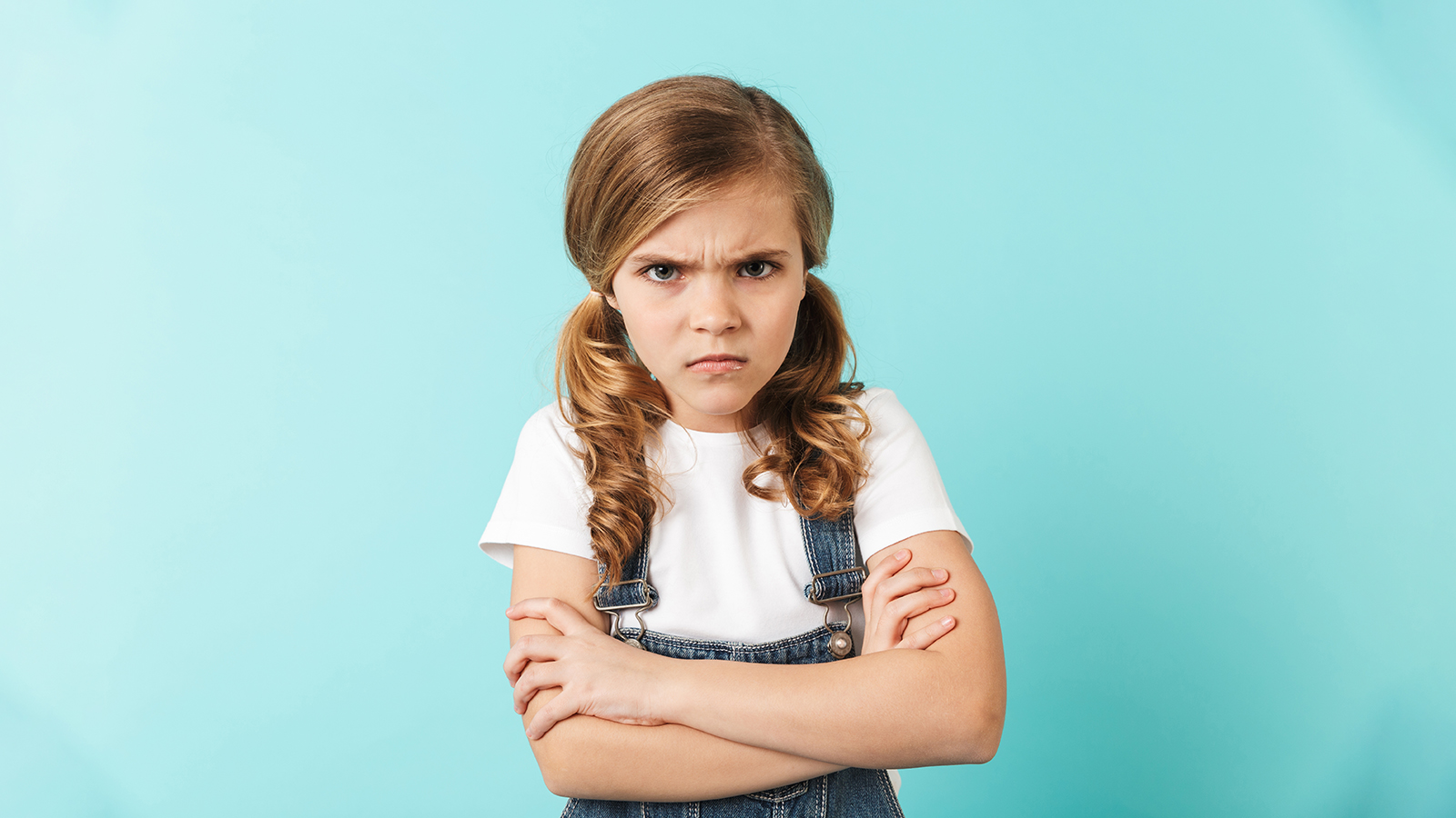 Image of pretty confused displeased young little girl posing isolated over blue wall background.