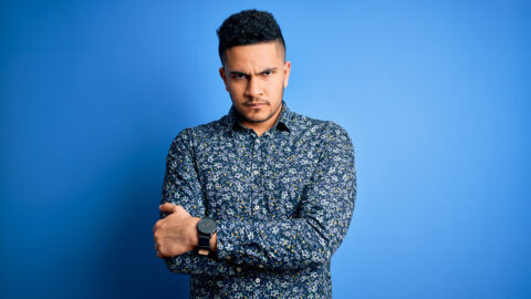 Young handsome man wearing casual shirt standing over isolated blue background skeptic and nervous, disapproving expression on face with crossed arms. Negative person.
