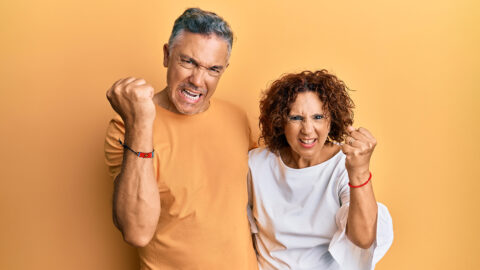 Beautiful middle age couple together wearing casual clothes angry and mad raising fist frustrated and furious while shouting with anger. rage and aggressive concept.