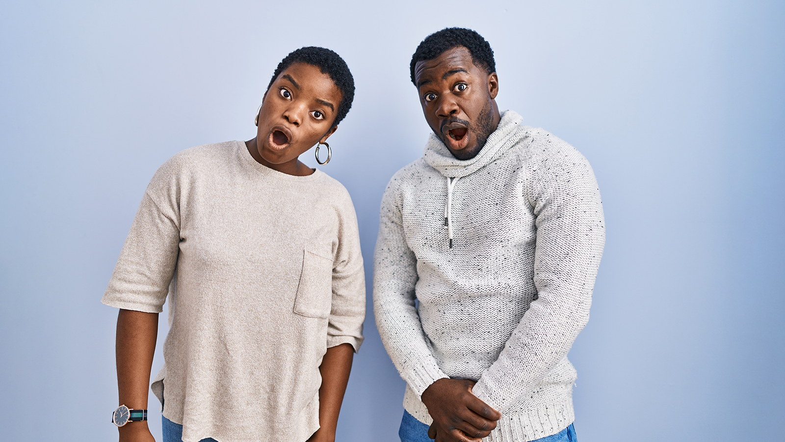 Young african american couple standing over blue background together in shock face, looking skeptical and sarcastic, surprised with open mouth