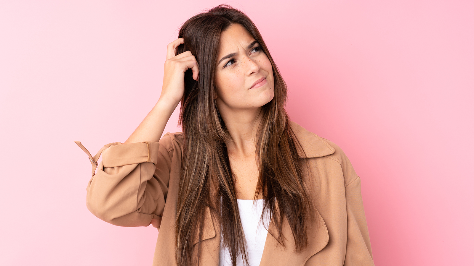 Teenager Brazilian girl over isolated pink background having doubts and with confuse face expression