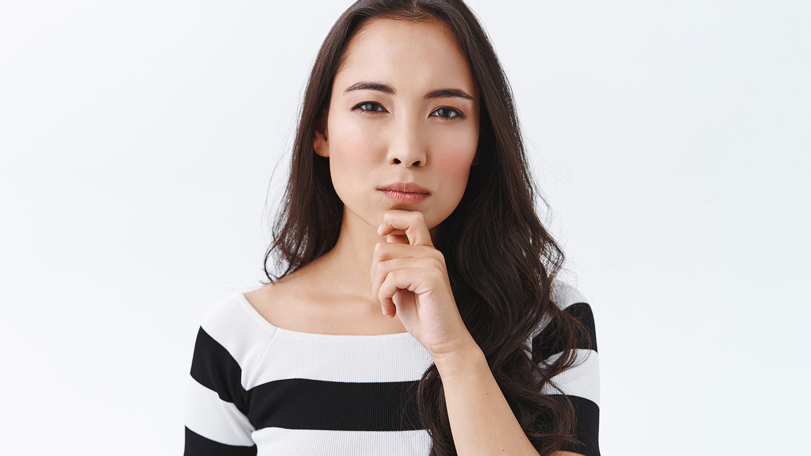 Judgemental serious-looking skeptical asian woman having doubts, staring pensive, touch chin thoughtful frowning and squinting as weighing up choices, thinking over white background