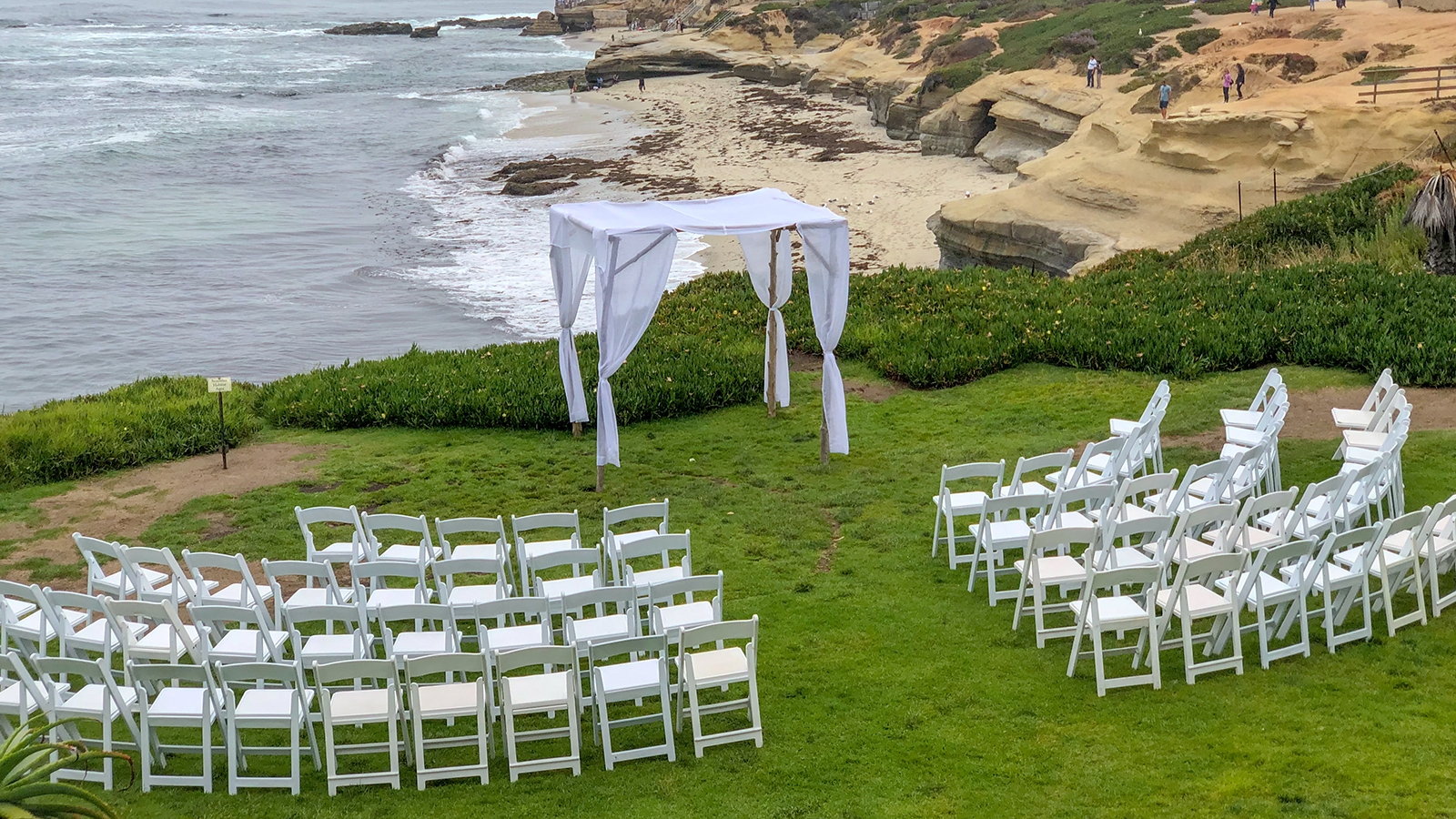 Wedding ceremony setting with white chairs and arch in the gard