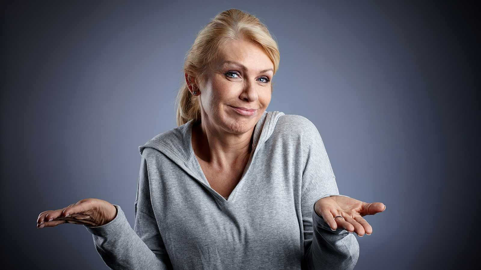 Portrait of mature woman shrugging over grey background
