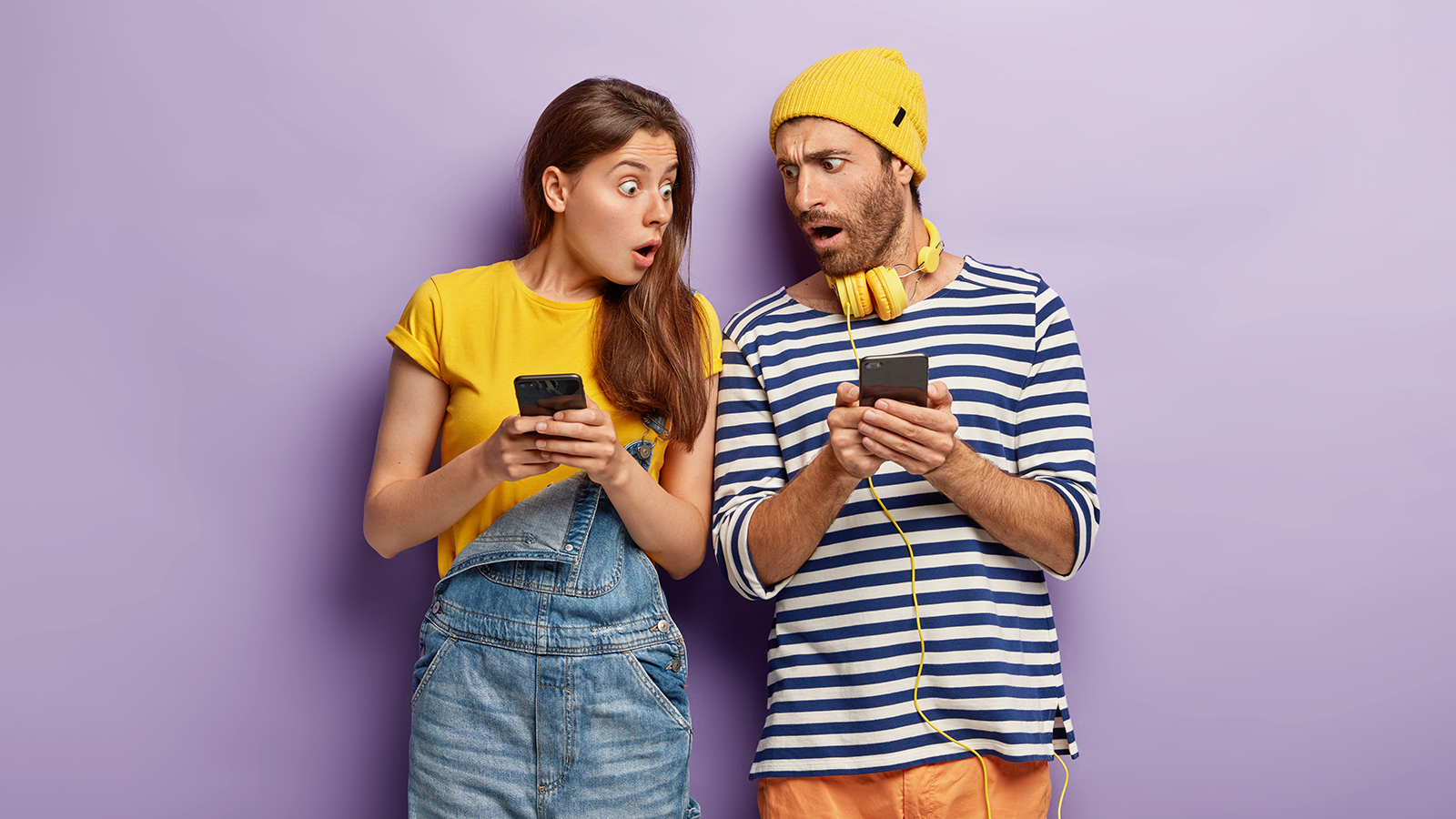 Fascinated surprised woman and man ignore real communication, scared of bad internet connection, cannot find answer on exam, feels intense, wear stylish clothes for youth isolated on purple background