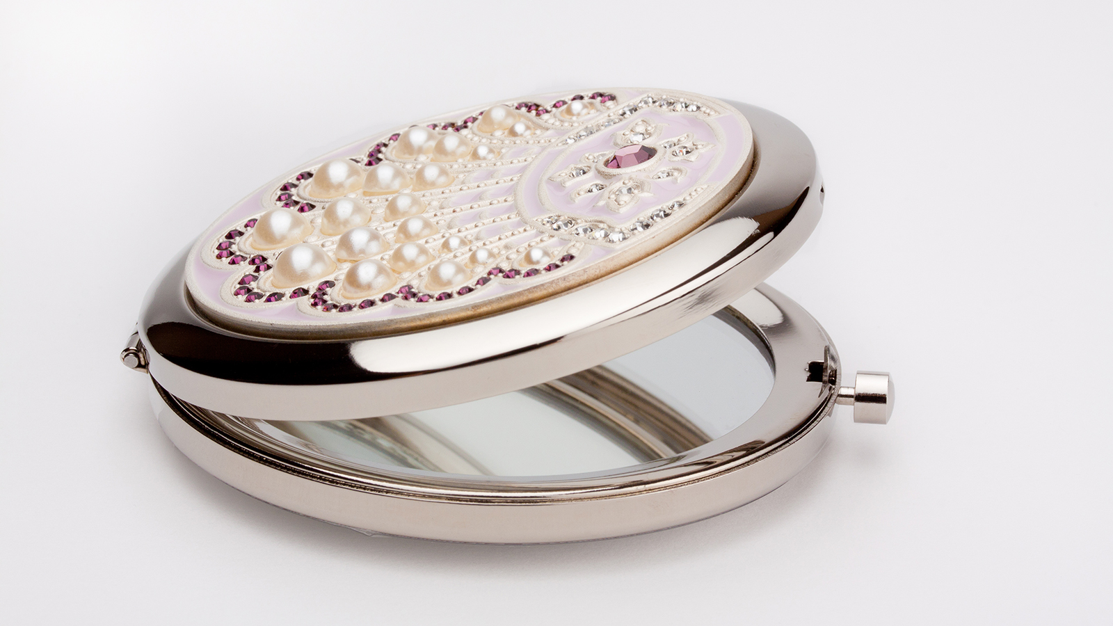 Round pocket makeup mirror with pearls and purple stones on white background