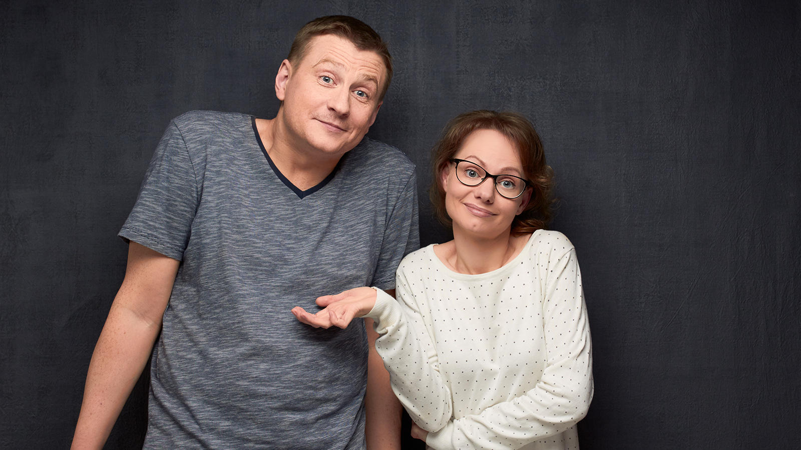 Half-length portrait of confused caucasian couple shrugging their shoulders being unsure and doubting, not knowing what to do or how this happened, looking uncertainly at camera, over gray background